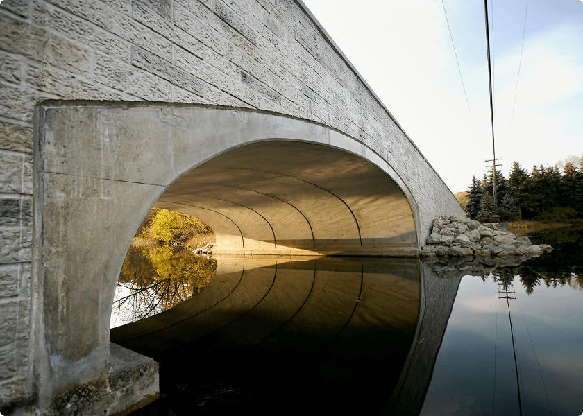 Bridge arching over calm reflective water.